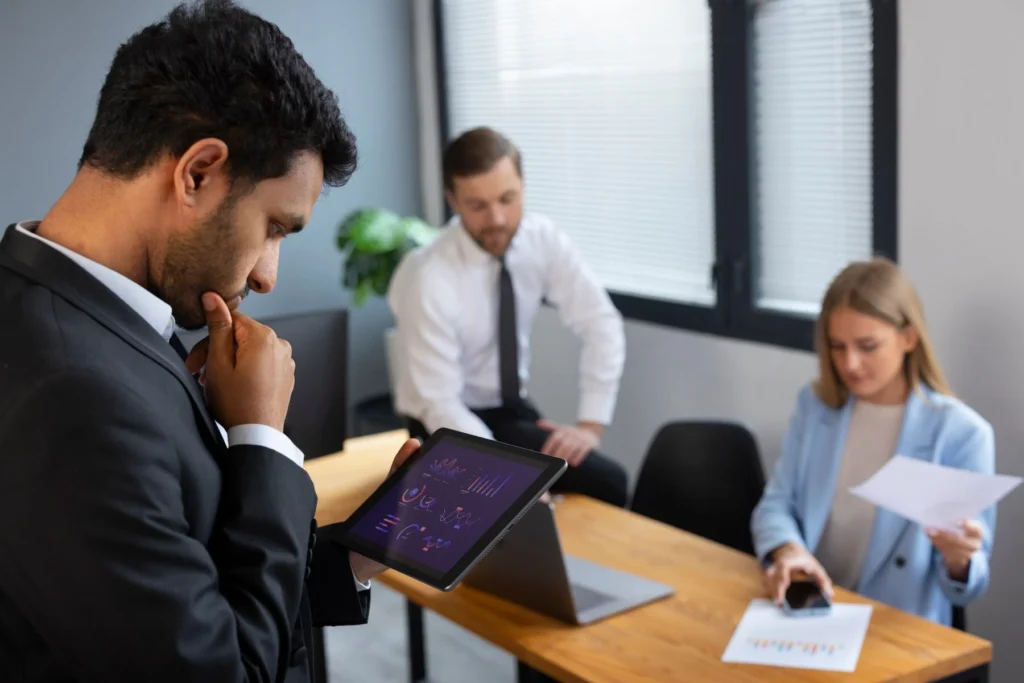 A professional analyzing data on a tablet during a business meeting.