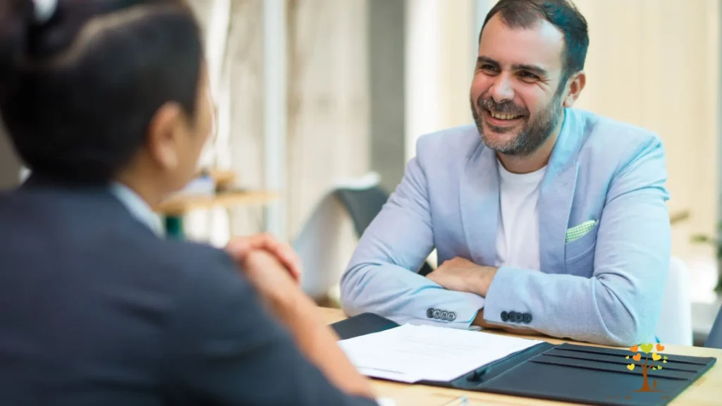 A man in a suit smiles warmly at a woman in a suit, conveying a sense of professionalism and camaraderie.