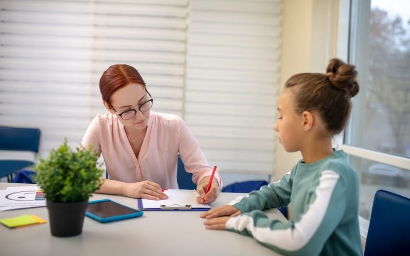 Handling Disclosures and Reporting Concerns A young girl receiving guidance from her teacher while working on a project.